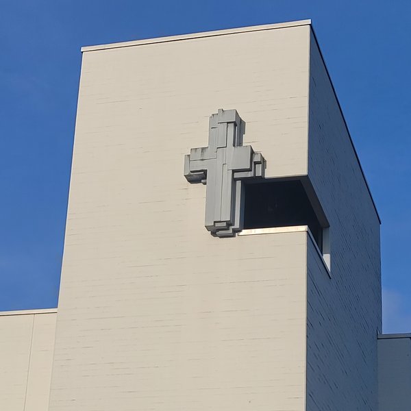 Kirchturm einer Kirche aus Beton mit Reliefkreuz