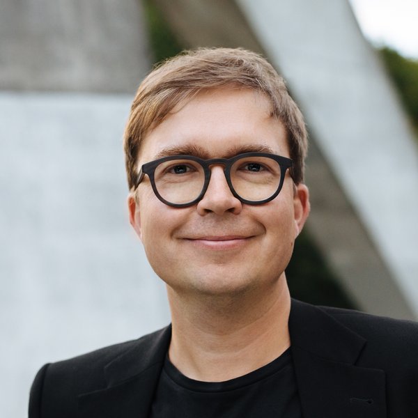 Schulterbild eines Mannes mit dunkelblondem Kurzhaarschnitt und schwarzer Brille