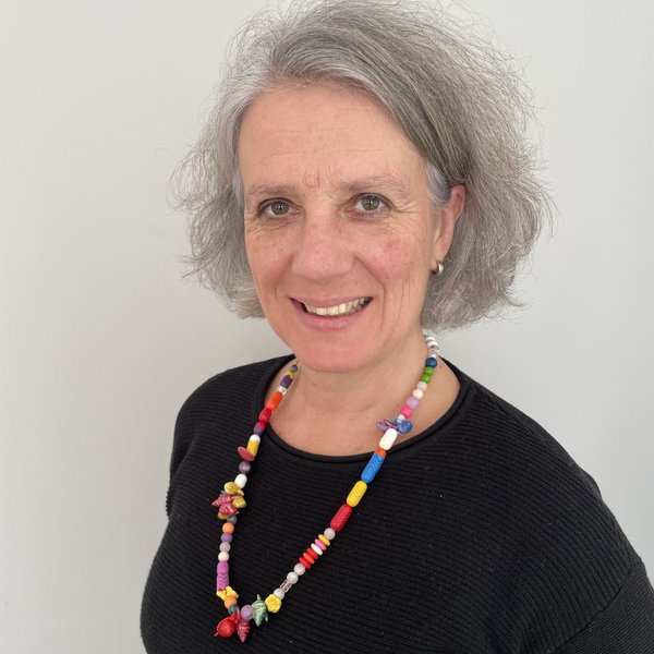 Schulterbild einer Frau mit halblangem grauen Haar und einer farbigen Halskette