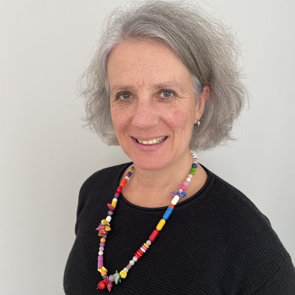 3.	Schulterbild einer Frau mit halblangem grauen Haar und einer farbigen Kette